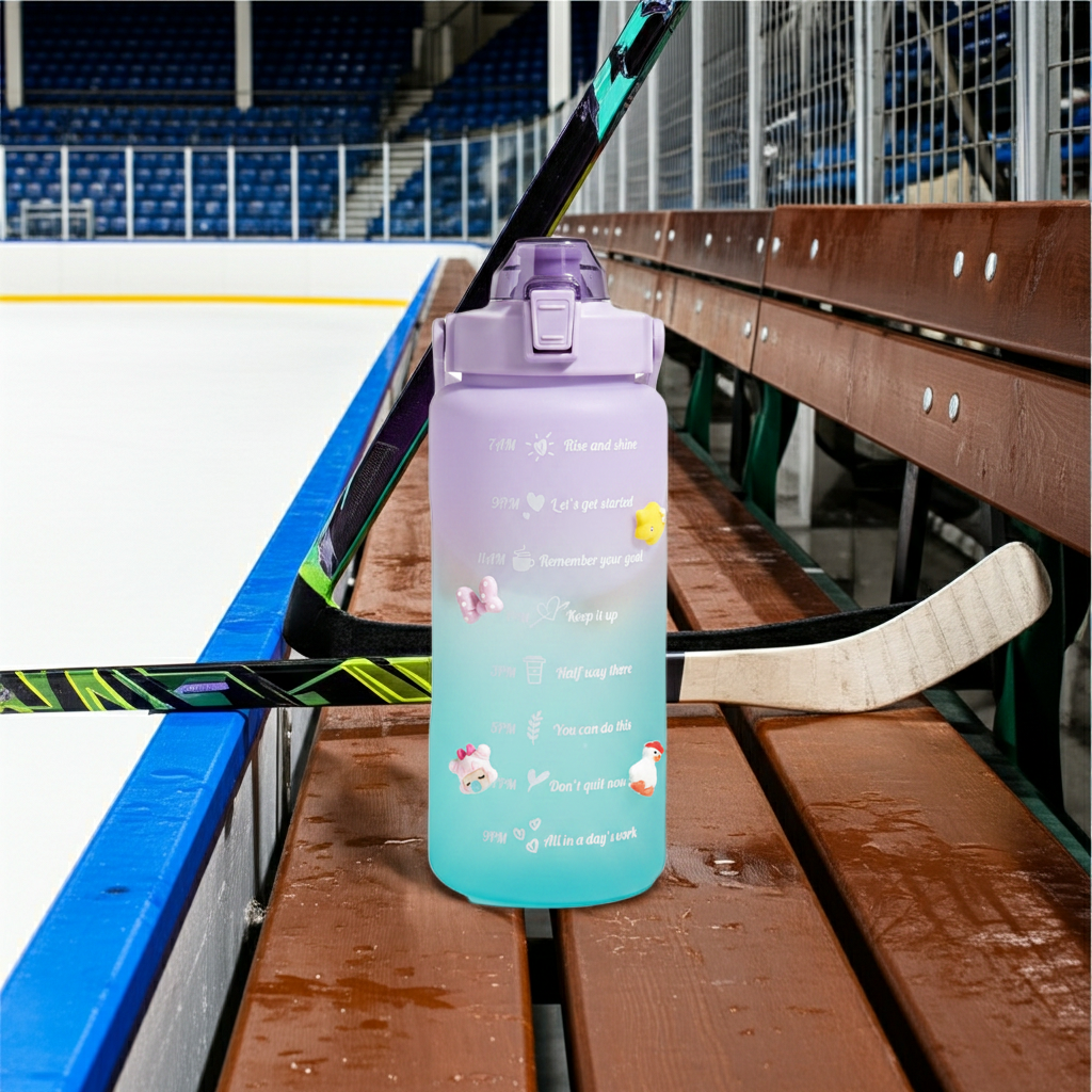 Aquatica HydroMark 2L Motivational Water Bottle — BPA-Free, Time-Marker Tracker, Straw Lid on the bench at a hockey rink 