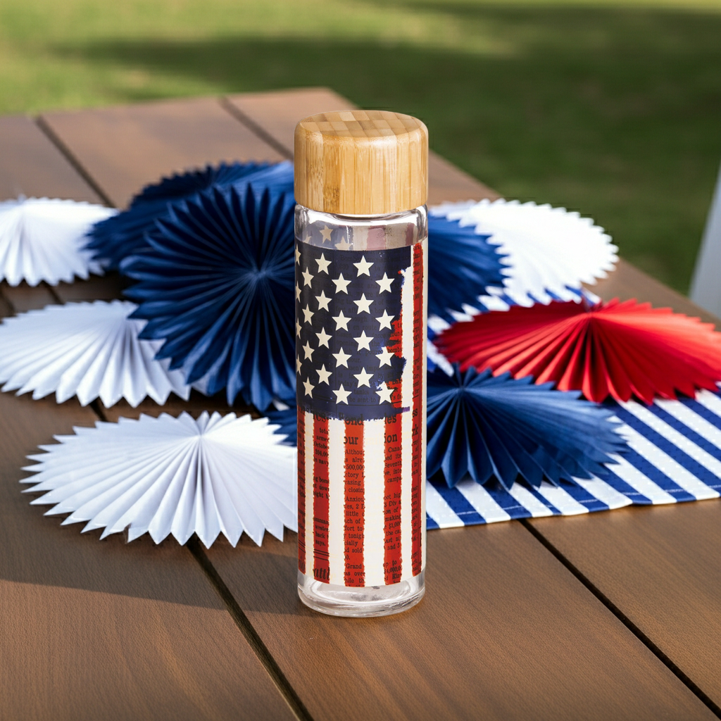 Land of Liberty Glass Water Bottle on a picnic table with red, white and blue fans