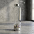 Fluorite Gemstone Glass Water Bottle with Black Sleeve in a gray studio setting